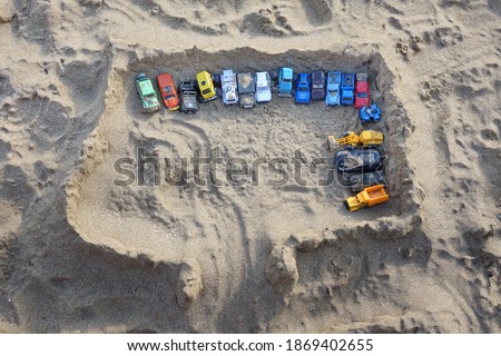 Sandcastle Top View On Sea Beach With Kids Toys. Sand Castle Or Fort With Many Colorful Plastic Car On Summer Sea Coast Overhead View. Abstract Background.
