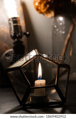 Candle in a Glass holder with an edison bulb and dried flowers in background