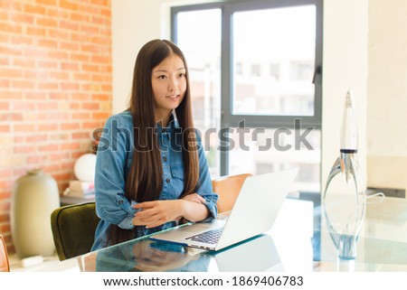 young asian woman doubting or thinking, biting lip and feeling insecure and nervous, looking to copy space on the side