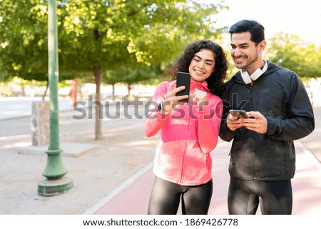 Pretty young woman taking a selfie with a good-looking guy before going on a run in the park