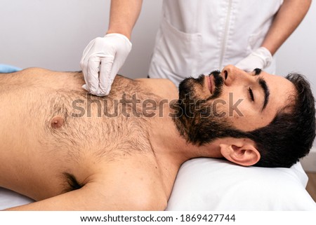 Stock photo of unrecognized worker doing a procedure with cotton to male client.