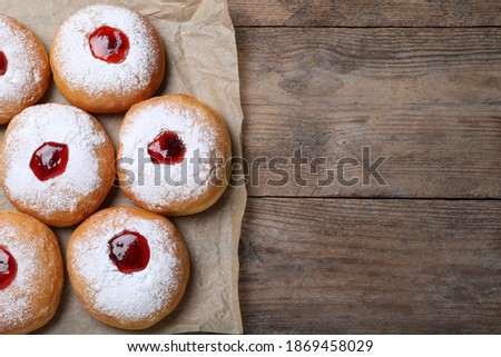 Hanukkah doughnuts with jelly and sugar powder on wooden table, flat lay. Space for text