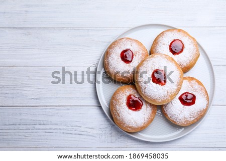 Hanukkah doughnuts with jelly and sugar powder on white wooden table, top view, Space for text