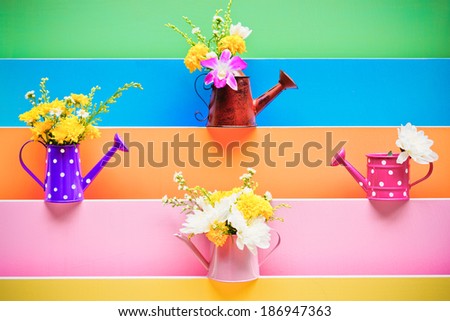 colorful wood texture with watering cans decorated with flowers 