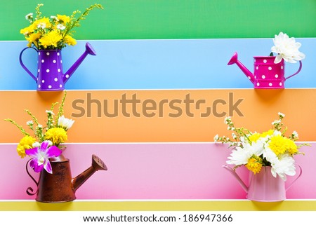colorful wood texture with watering cans decorated with flowers 