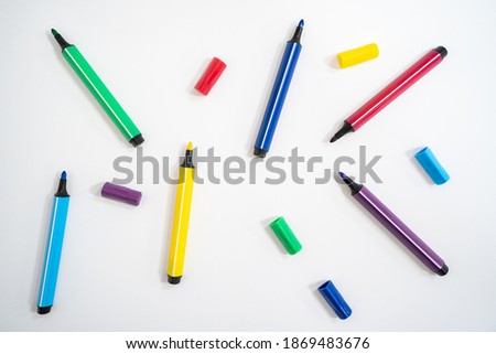 Colorful marker pens with caps removed on a white background. Close-up photo