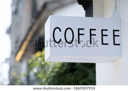White coffee signage on the wall with green plants on background 