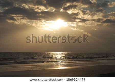 Picture of q sunset through clouds on a beach.