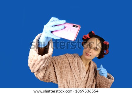 Young housewife girl with curlers on head takes a selfie on phone