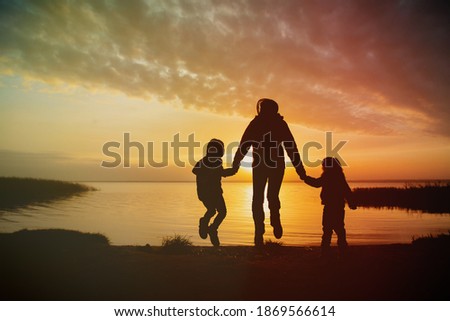 happy mother with kids looking at sunset on lake