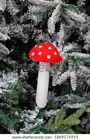 Christmas toy fly agaric hanging on Christmas tree in the snow