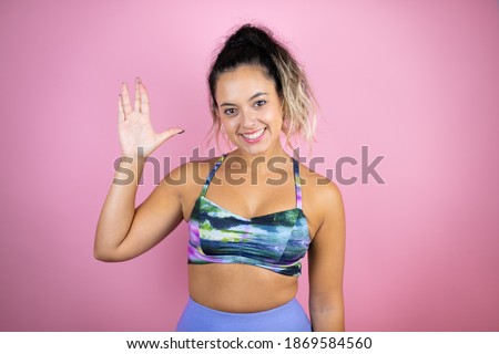 Young beautiful woman wearing sportswear over isolated pink background doing hand symbol