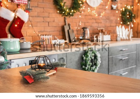 Aroma candle with Christmas decor on table in kitchen