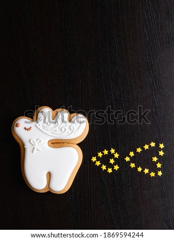 Valentine Day. Fun greeting card. Festive background. Bakery food holiday decoration. White gingerbread fantasy badass deer farting with gold star hearts on black wooden texture empty space.