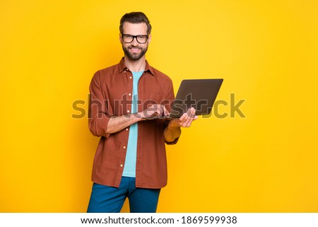 Photo of young smiling cheerful good mood positive man businessman working in laptop isolated on yellow color background