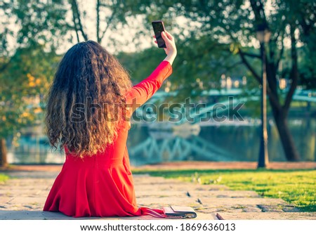 Rear View Beautiful teenage girl taking selfie posing in autumn park