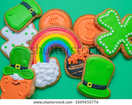 Top view of freshly baked St. Patricks Day decorated sugar cookies on green background. Homemade cookies with shamrock, rainbow, leprechaun and pot of gold decorations. Irish holiday