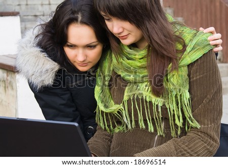 Two students studying outdoor with laptop