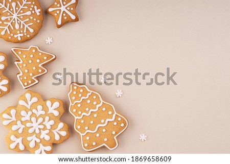 Christmas gingerbread on a soft pastel background with space for text. Snowflakes and Christmas trees are scattered on the table