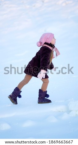 Winter picture of a little girl. Against the background of snow