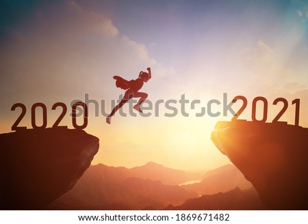 Silhouette of a child jumping between 2020 and 2021 against the sunset, the concept of a successful New year. Royalty-Free Stock Photo #1869671482