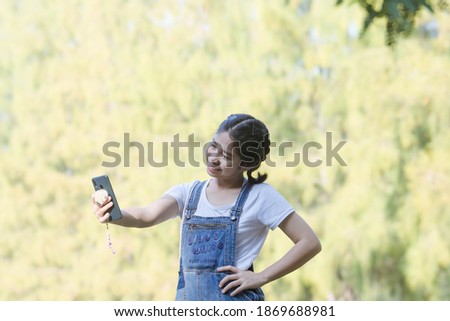 asian cute girl holding camera in hand and take a picture with selfie shot in park