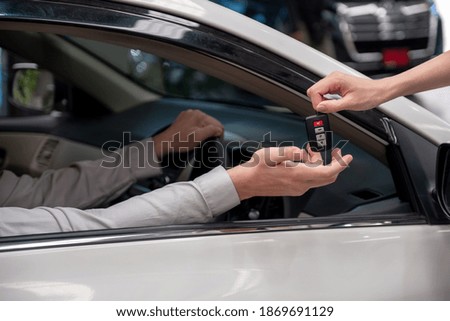 Hand of car rental agency giving car key to customer hand in side car.
