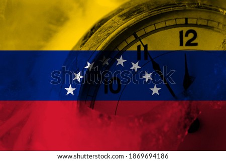Venezuela flag with clock close to midnight in the background. Happy New Year concept