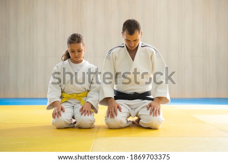 Judo master and young yellow belt judo girl in white judogi kneeling  Royalty-Free Stock Photo #1869703375