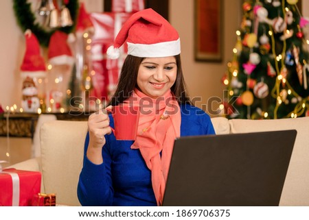 Young Women wearing Christmas cap working on laptop sipping coffee at home on Christmas day