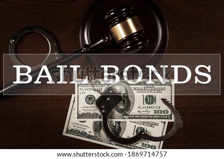 Bail bonds services concept. Judge gavel, handcuffs and money on wooden background. Royalty-Free Stock Photo #1869714757