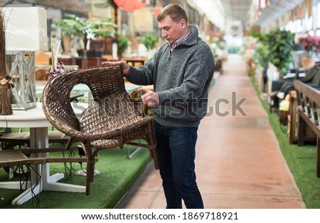 Customer man standing with wicker chair in shop for decor. High quality photo