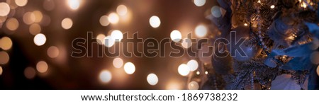 Festive background with a decorated Christmas tree, New Year's toys, holiday lights, neon lights and garland. Dark background with blurred bokeh.