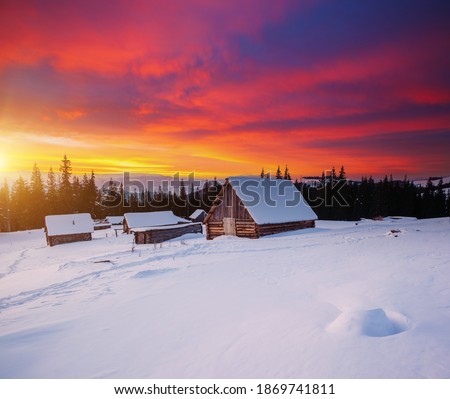 Snow-capped mountain huts in the frosty evening. Location place Carpathian mountains, Ukraine, Europe. Christmas holiday concept. Vibrant photo wallpaper. Happy New Year! Discover the beauty of earth.