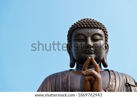 Wooden Buddha statue under blue sky.