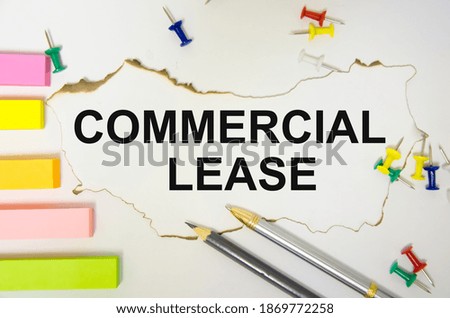 the text commercial lease is written on a white sheet of paper and on a white background there are stickers around the pen and notepad. High quality photo