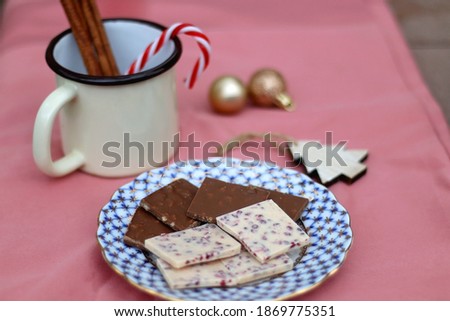 Chocolate pieces, vintage dishes and Christmas decorations. Selective focus, pink background. 