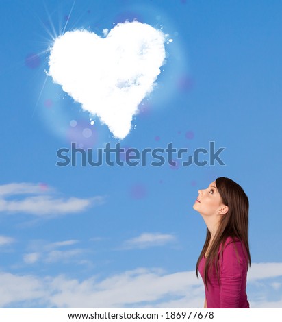 Cute girl looking at white heart cloud on blue sky concept