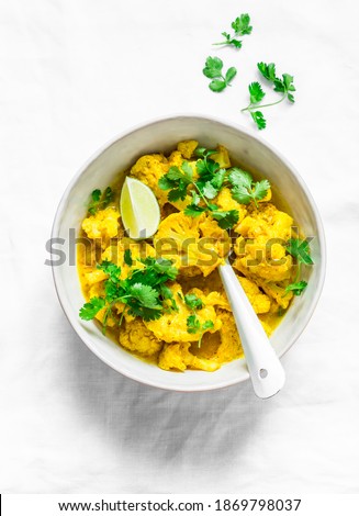 Vegetarian indian cauliflower stew with curry sauce, cilantro, lime on light background, top view. Delicious indian food concept        Royalty-Free Stock Photo #1869798037