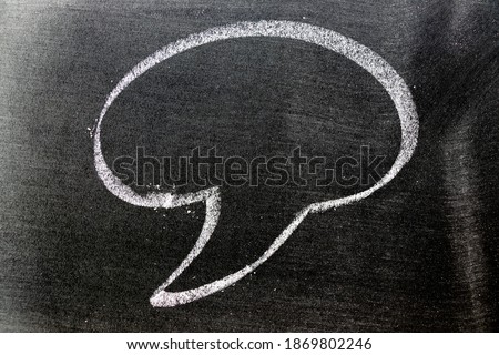 White color chalk hand drawing in round bubble speech shape with blank space on black board background