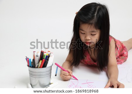 The Asian girl drawing picture on the white background.