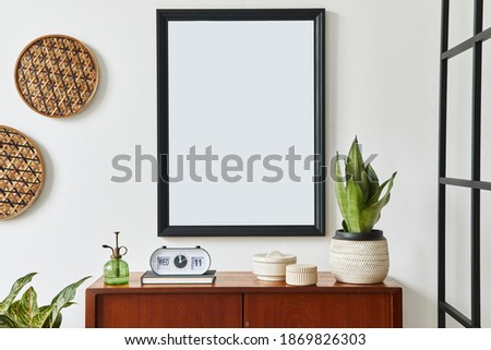 Retro modern compositon of living room interior with design teak commode,  black mock up poster frame, clock, plant, decoration, white wall and personal accessories. Template.