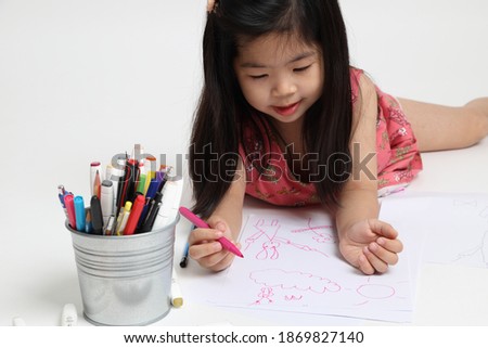 The Asian girl drawing picture on the white background.