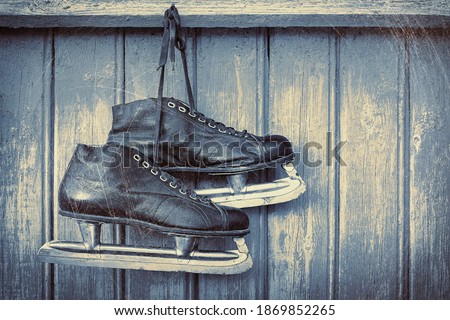Old hockey skates hanging on a blue wooden wall.Toned photo
