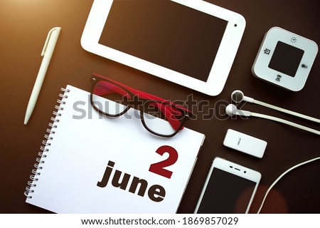 June 2nd. Day 2 of month, Calendar date. Office workplace with laptop, notebook, office supplies and stationery on brown back. Summer month, day of the year concept