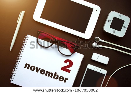 November 2nd. Day 2 of month, Calendar date. Office workplace with laptop, notebook, office supplies and stationery on brown back. Autumn month, day of the year concept