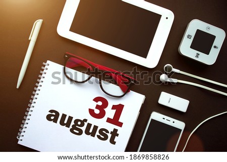 August 31st . Day 31 of month, Calendar date. Office workplace with laptop, notebook, office supplies and stationery on brown back. Summer month, day of the year concept