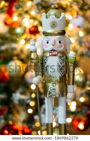 Christmas nutcracker with bokeh Christmas tree background. Golden and white in color. Close up. Royalty-Free Stock Photo #1869862276