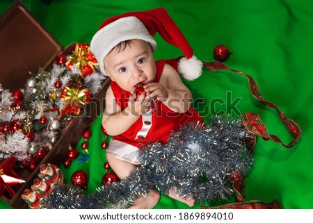 
cute boy with christmas tree. happy baby sitting near a fir tree and holding a christmas ornament and smiling
