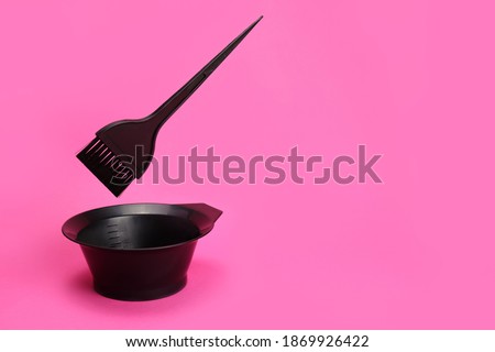 Bowl for hair coloring and levitating a brush on a pink background. Copy space Royalty-Free Stock Photo #1869926422